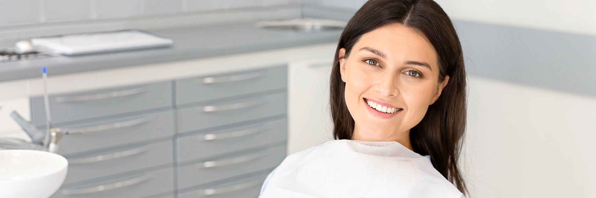 A well-lit reception area with a desk, computer monitor, and potted plant.